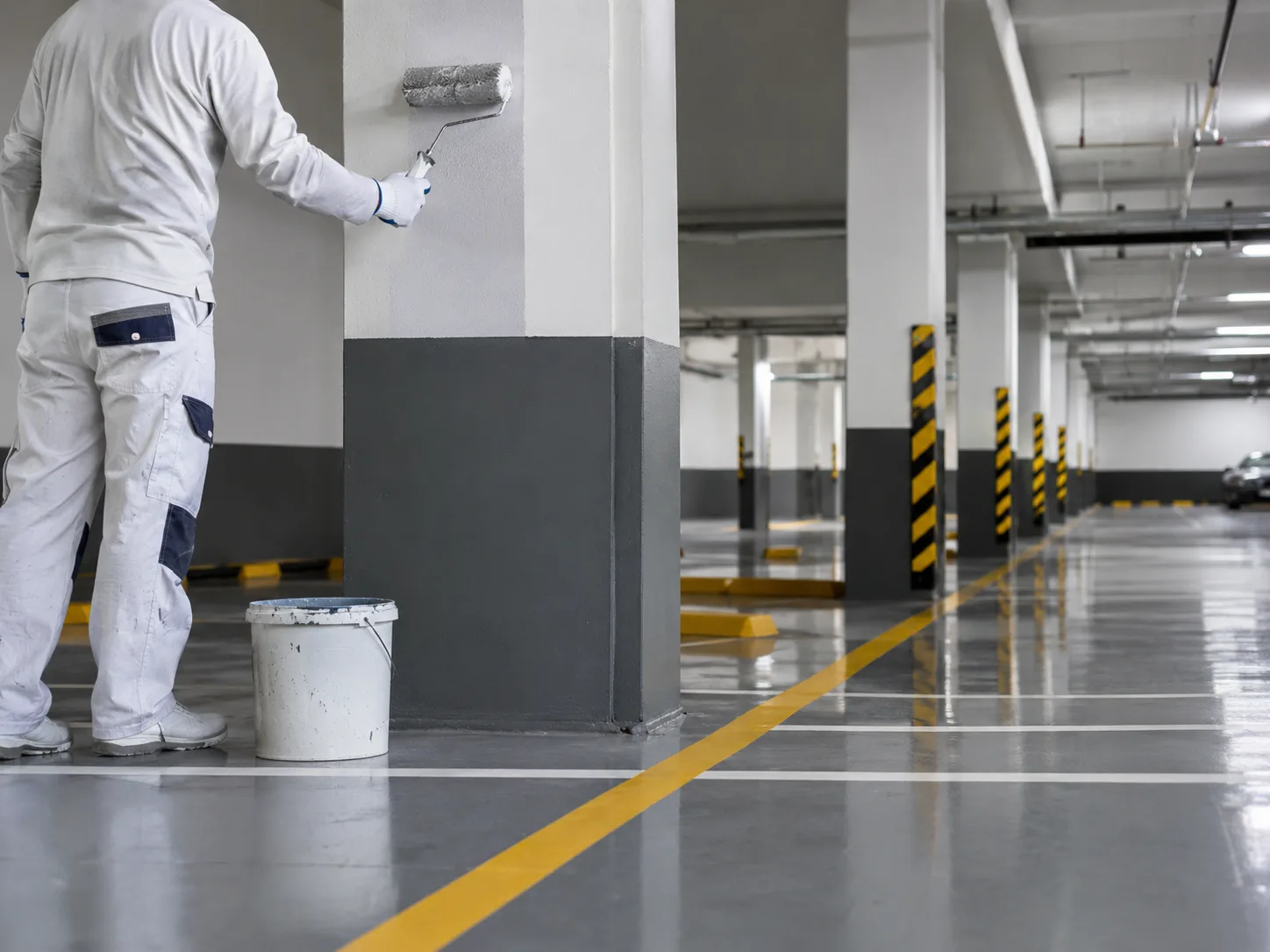 Protected painter applying a specialty coating to a structural column inside a parking structure in Toronto